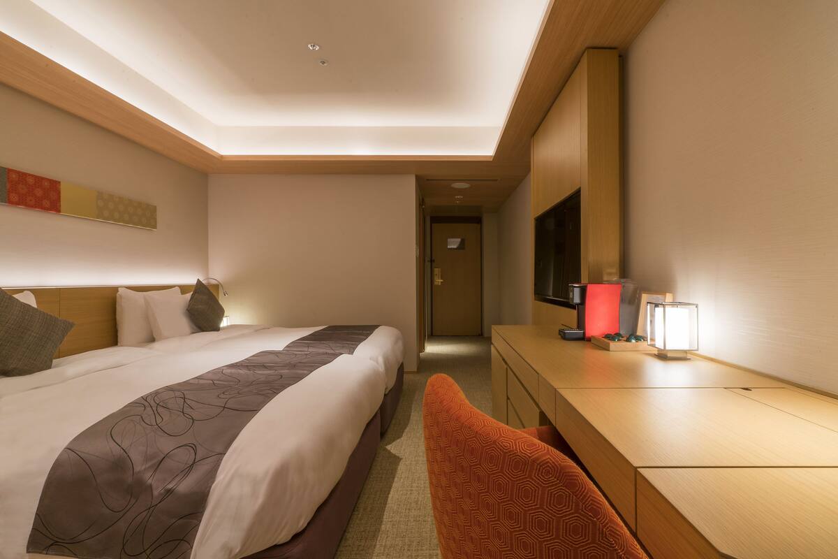 A hotel room with a large bed, a desk with a lamp, and a television.