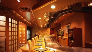 Een restaurant met een lange toonbank, houten lambrisering en een sushi-bar.