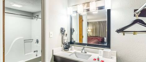Un baño moderno con bañera, inodoro, lavabo y un espejo grande con iluminación.