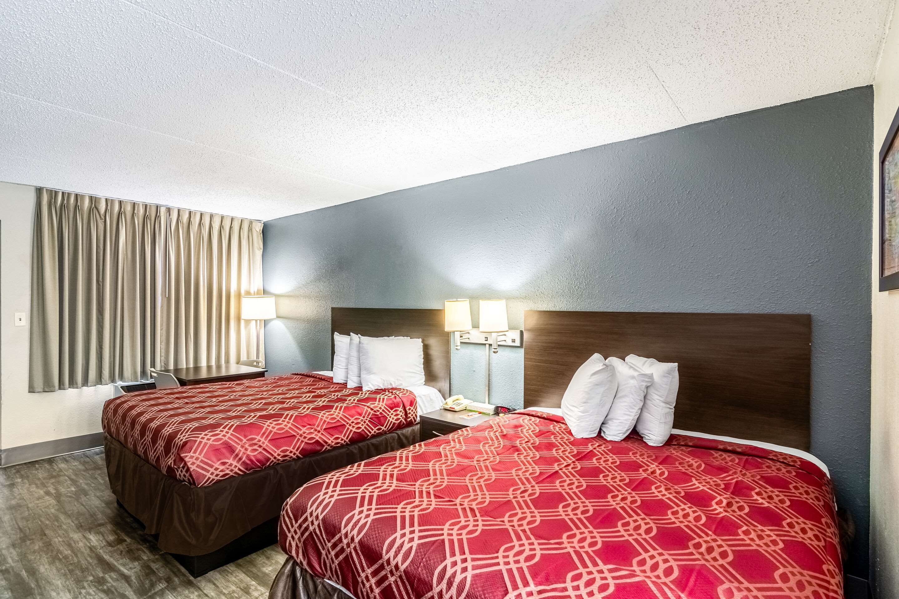 Habitación de hotel con dos camas, un escritorio y una silla.