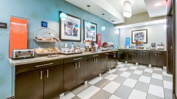 Una cocina moderna con piso a cuadros, electrodomésticos de acero inoxidable y una mesa de buffet.