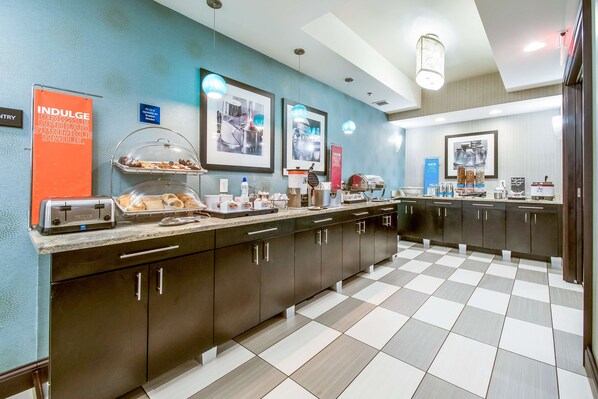 A modern kitchen with a checkered floor, stainless steel appliances, and a buffet setup.