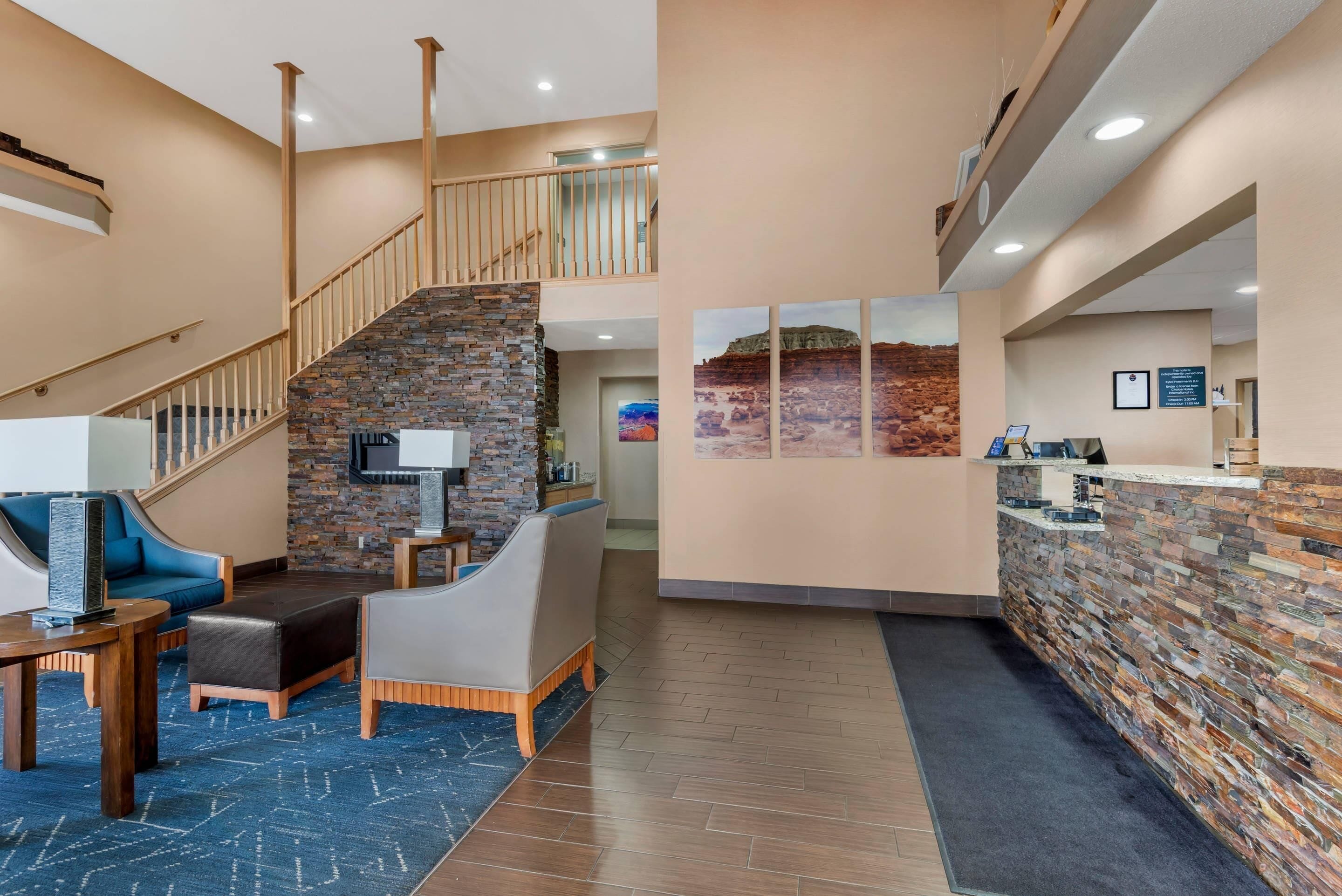 A lobby with a reception desk, a staircase with a stone wall, and seating areas.