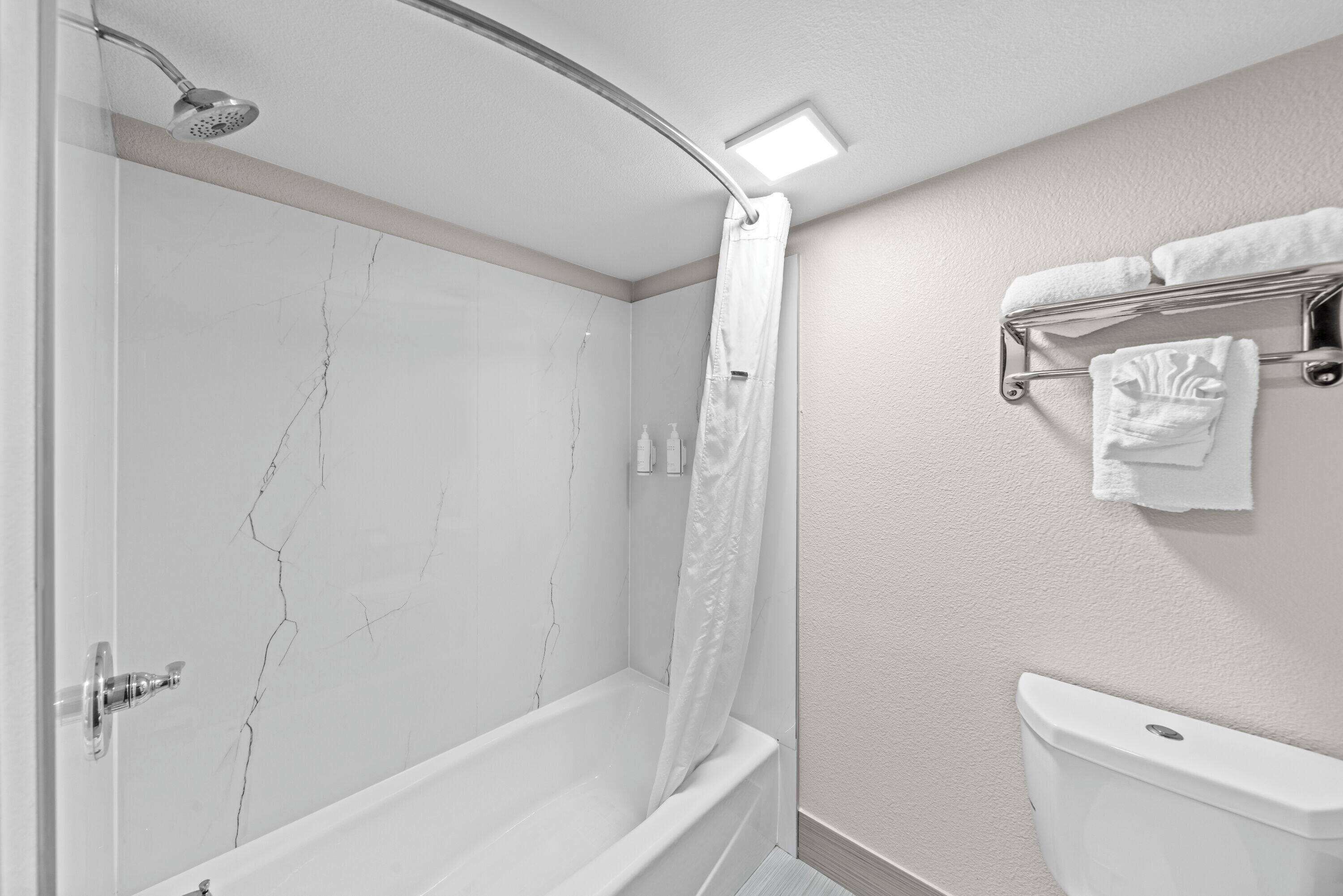 A bathroom with a bathtub, shower, and toilet.