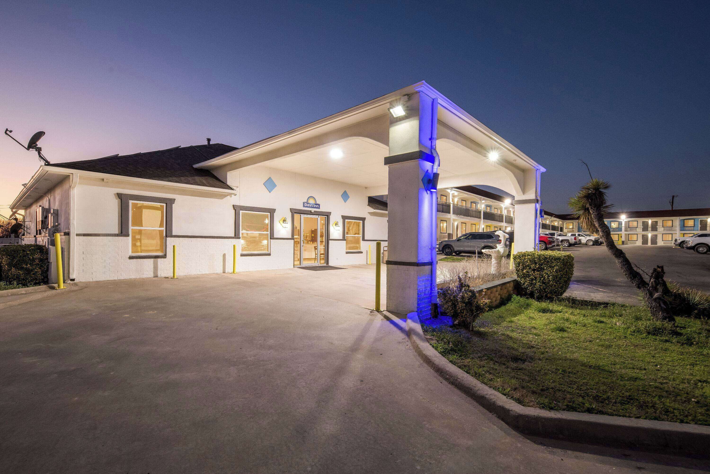 A hotel with a covered entrance, a signboard, and a parking area.