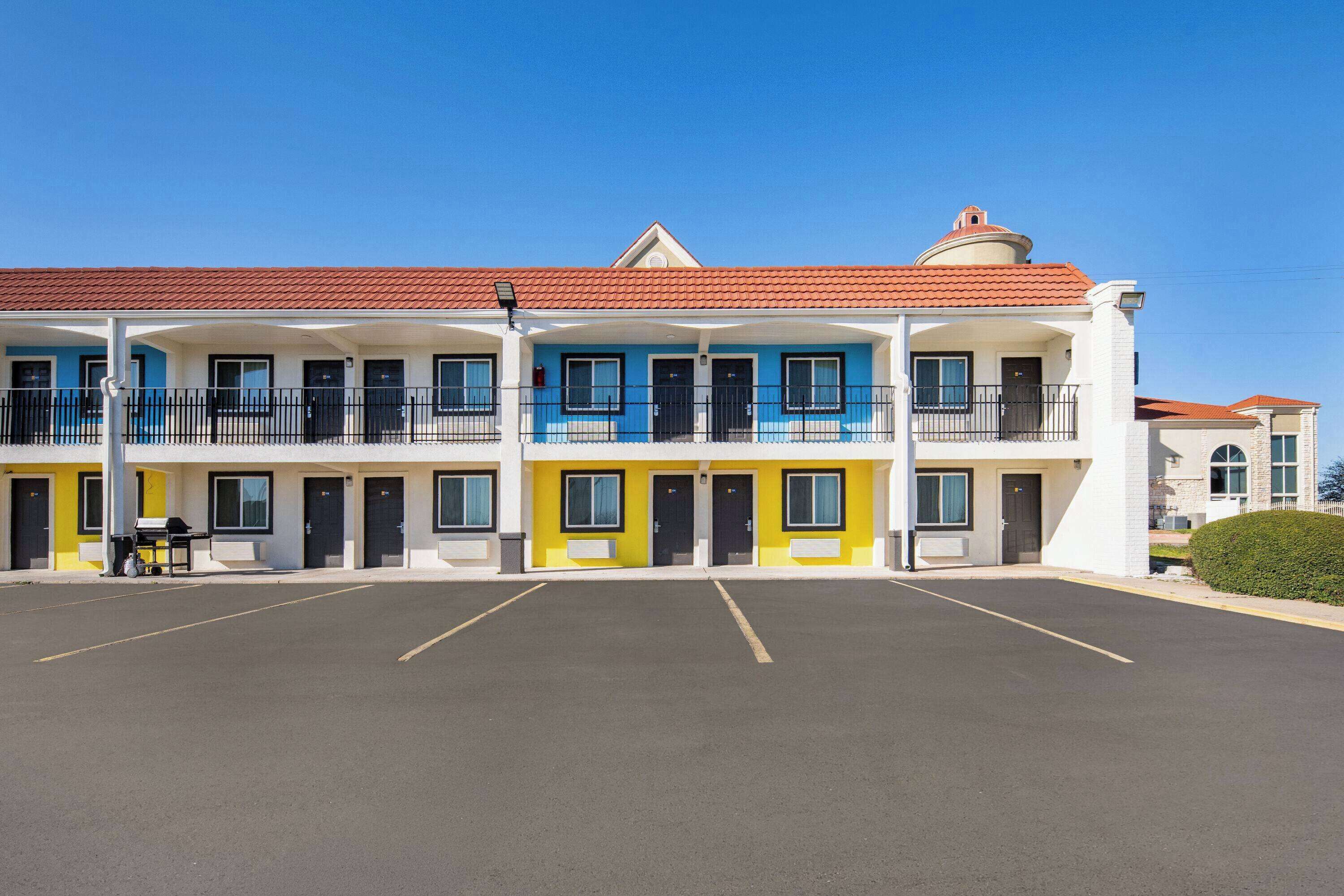 A multi-story motel with a parking lot in front.
