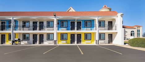 A multi-story motel with a parking lot in front.