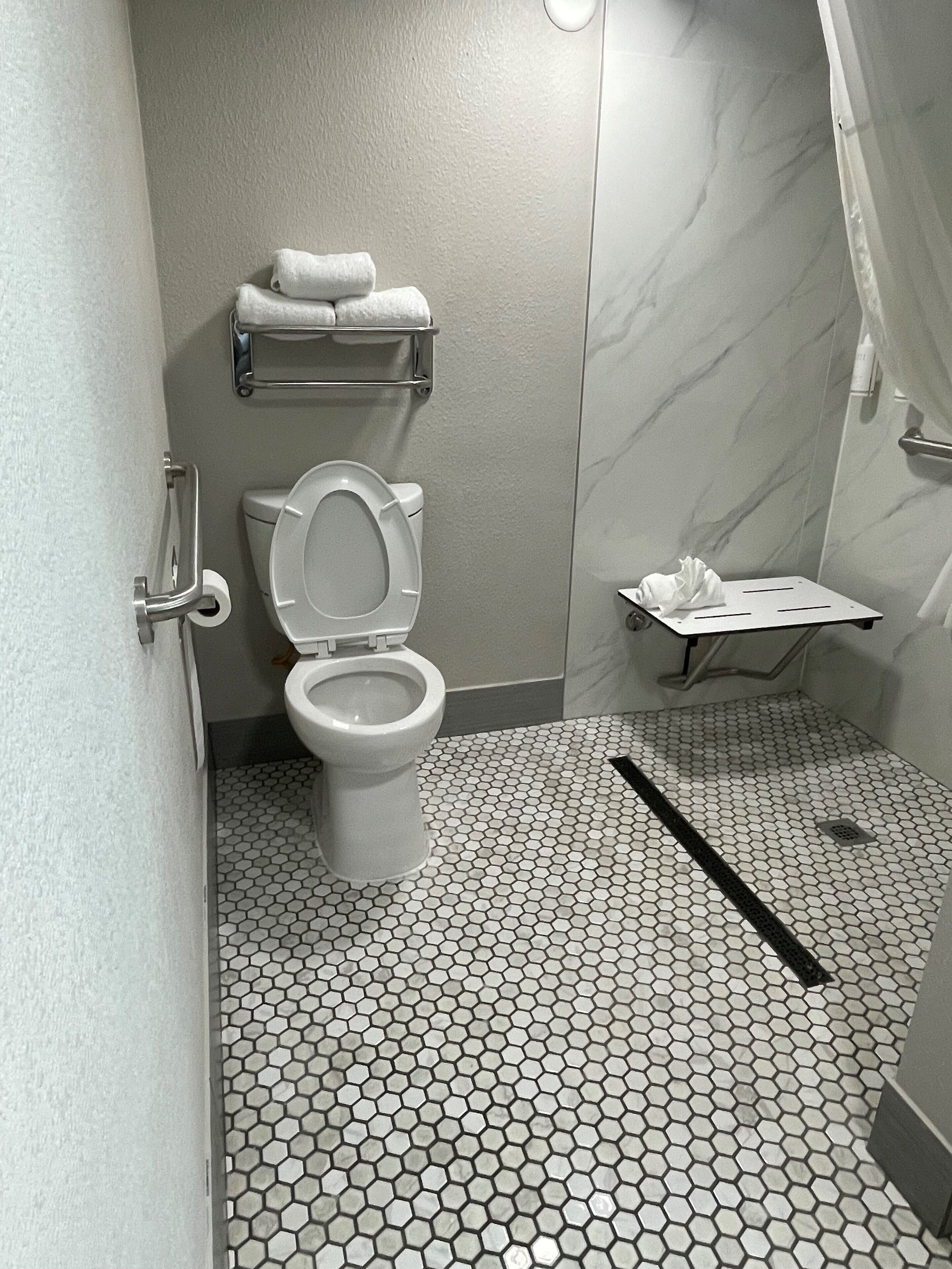 A bathroom with a toilet, a towel rack, a shower area, and a tiled floor.