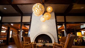 A cozy lobby with a fireplace, leather armchairs, and decorative hanging lamps. - The Garland (North Hollywood)