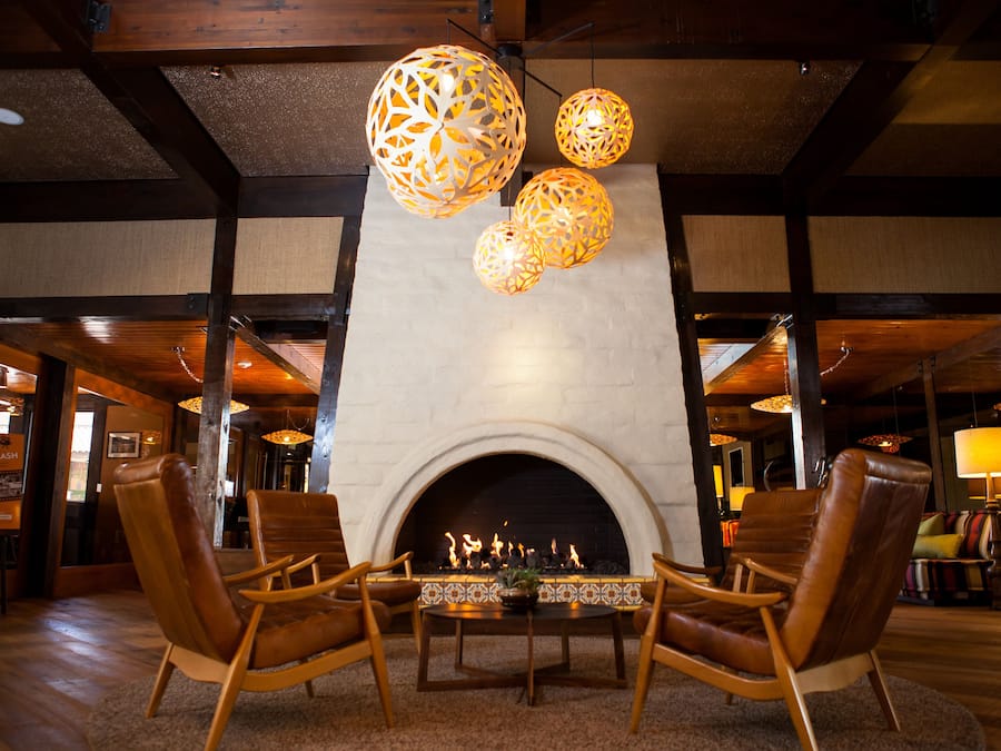 A cozy lobby with a fireplace, leather armchairs, and decorative hanging lamps.