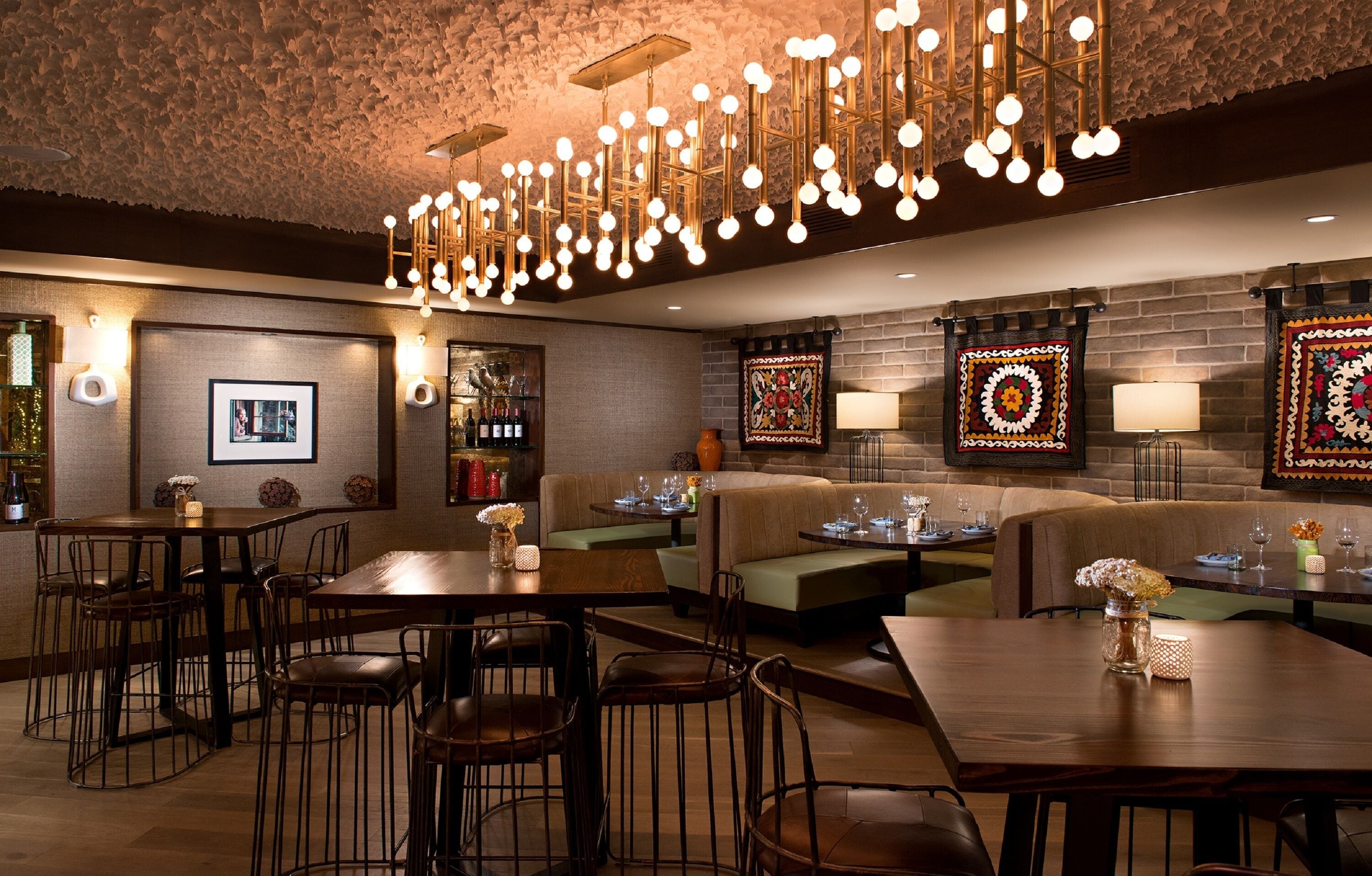 Un ristorante con tavoli alti e banconi, illuminazione calda e decorazioni a parete.