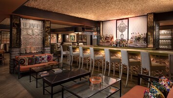 A cozy bar area with a bar counter, seating, and a decorative macramé wall.