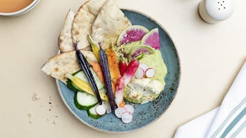 A plate with a variety of vegetables and flatbread, accompanied by a cup of tea.