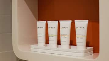 Una repisa con cuatro productos de limpieza corporal Lather en un baño.