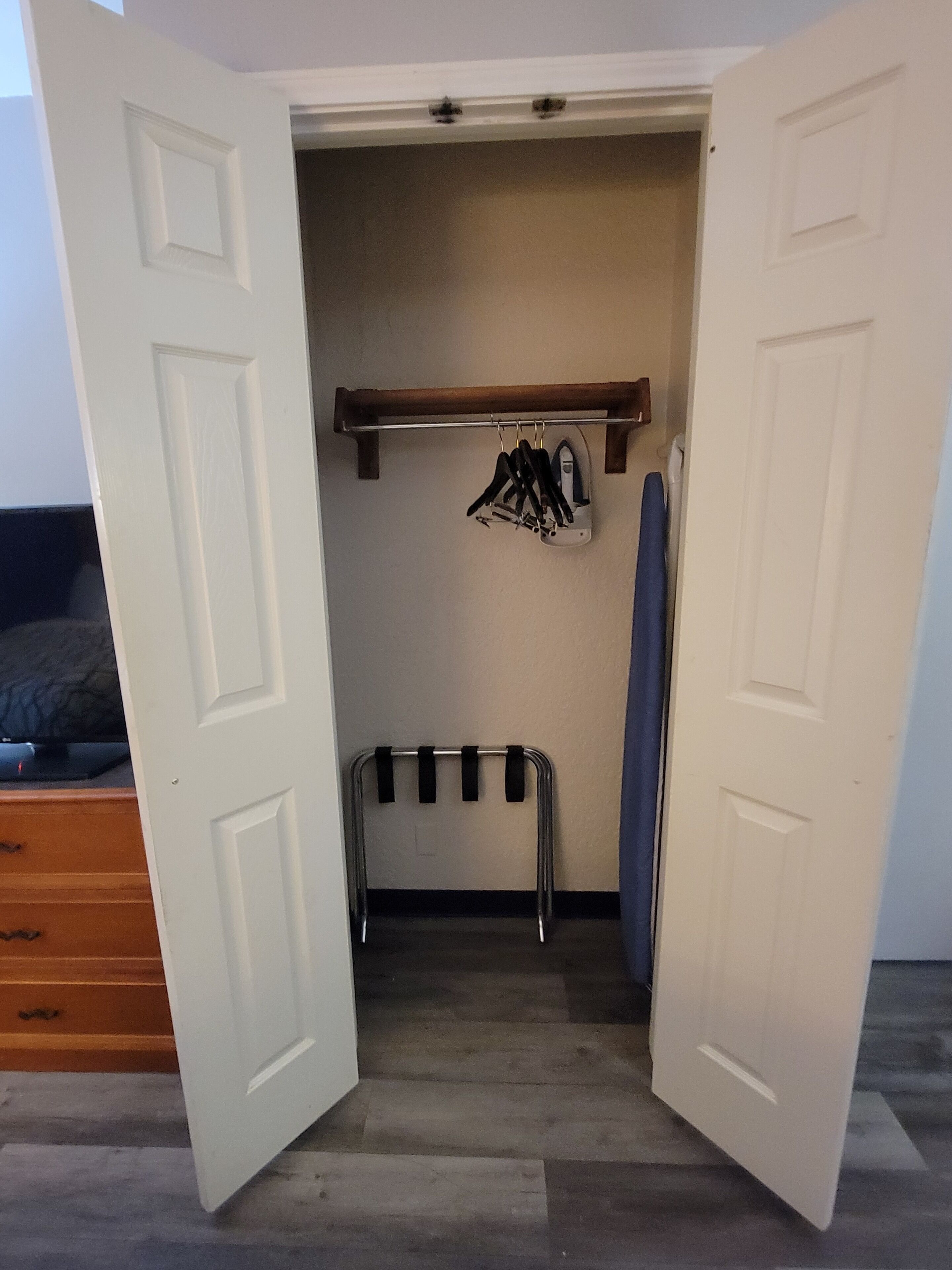 Un vestidor con una percha, una estantería metálica y una toalla azul.
