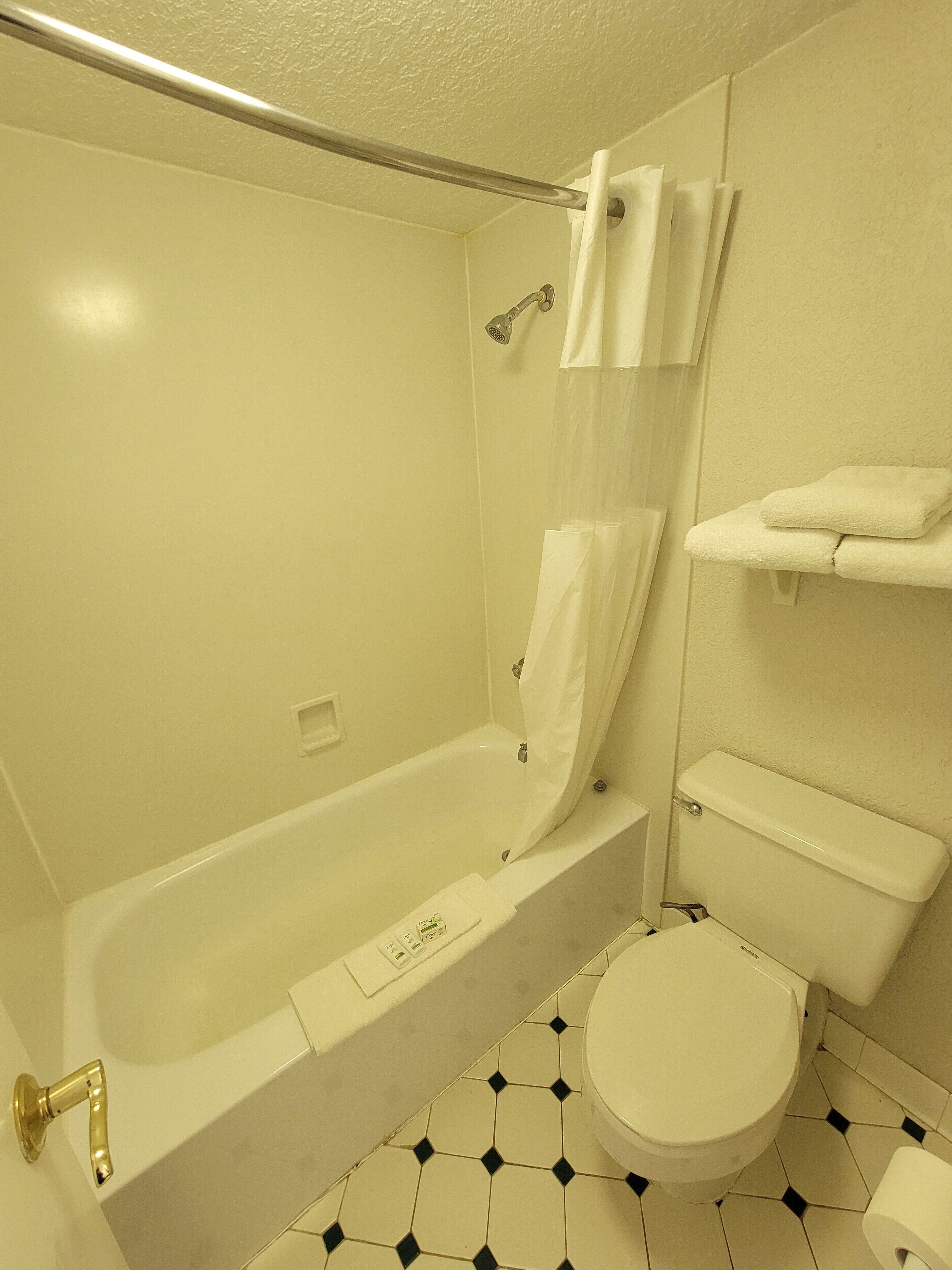 Une salle de bain avec une baignoire, des toilettes et une étagère avec des serviettes.