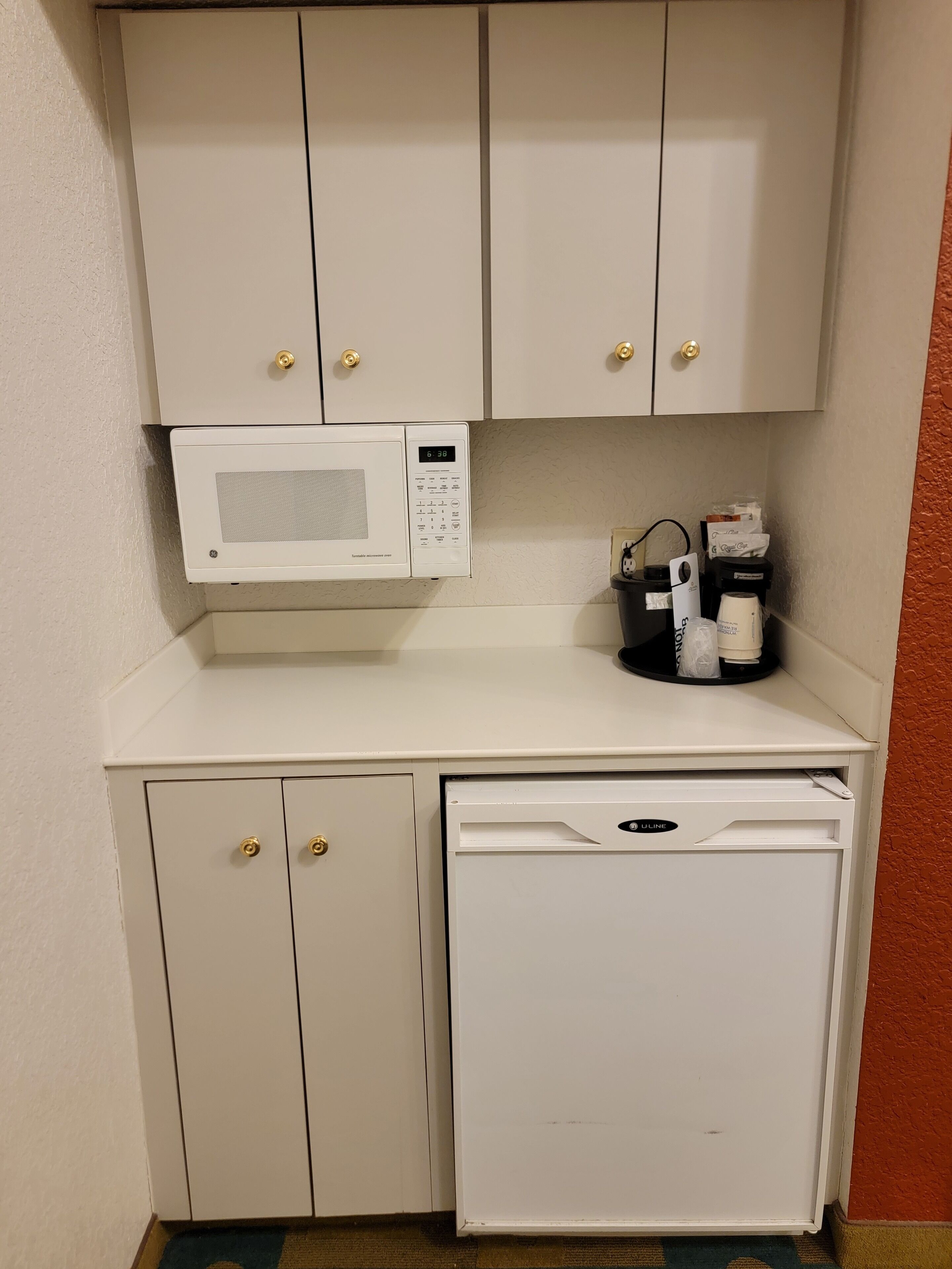 Eine kleine Küchenzeile mit Mikrowelle, Kaffeemaschine und Geschirrspüler.
