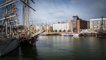 Een haven met een groot zeilschip afgemeerd, omringd door gebouwen en andere boten.