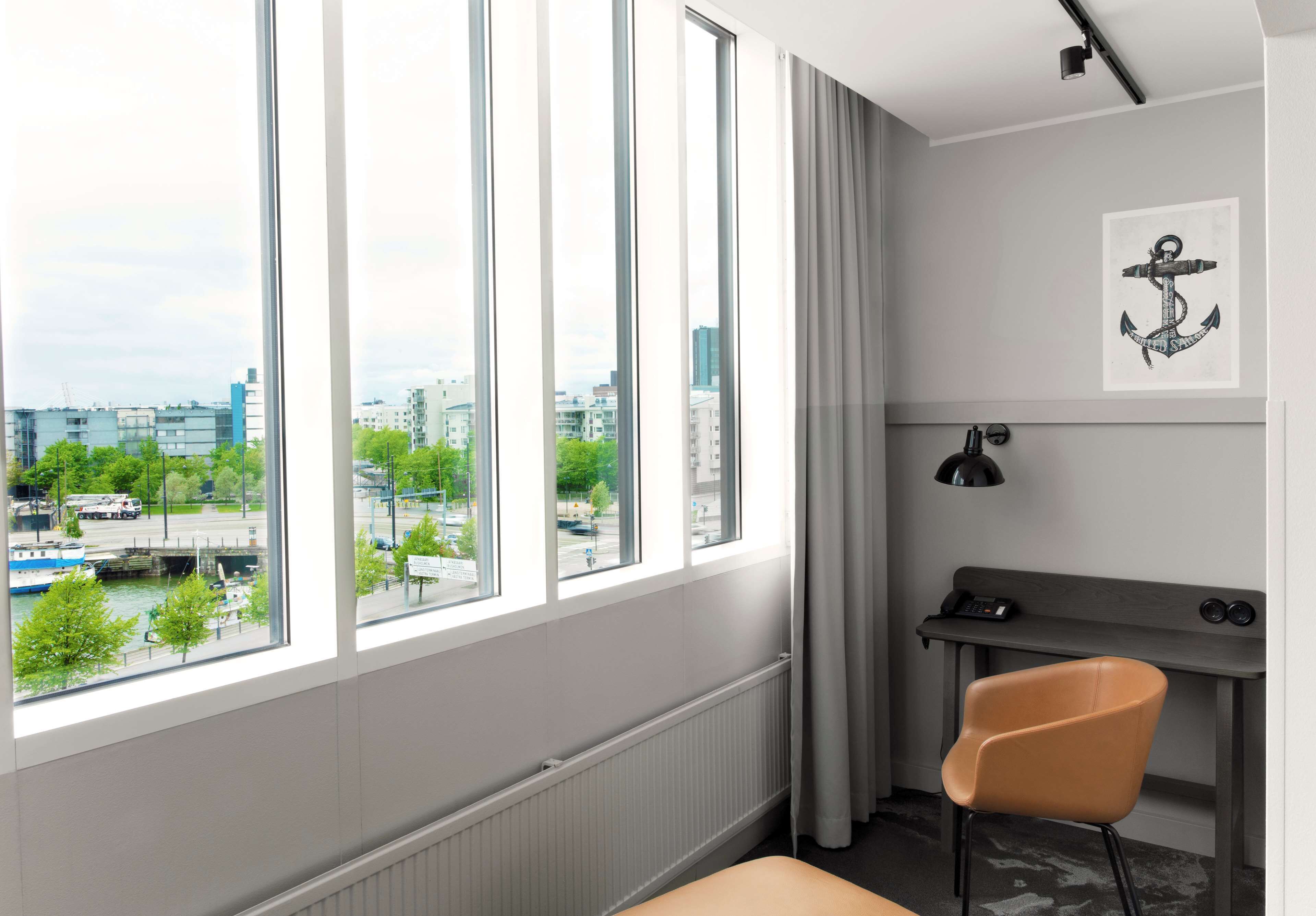 A modern room with large windows, a desk, a chair, and a view of a cityscape.
