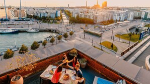 A rooftop terrace with a dining table, seating, and a view of the cityscape and water. - Radisson Blu Seaside Hotel, Helsinki (Helsinki)