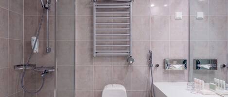 Un baño moderno con ducha envuelta en vidrio, inodoro blanco, perchero y tocador con artículos de aseo.