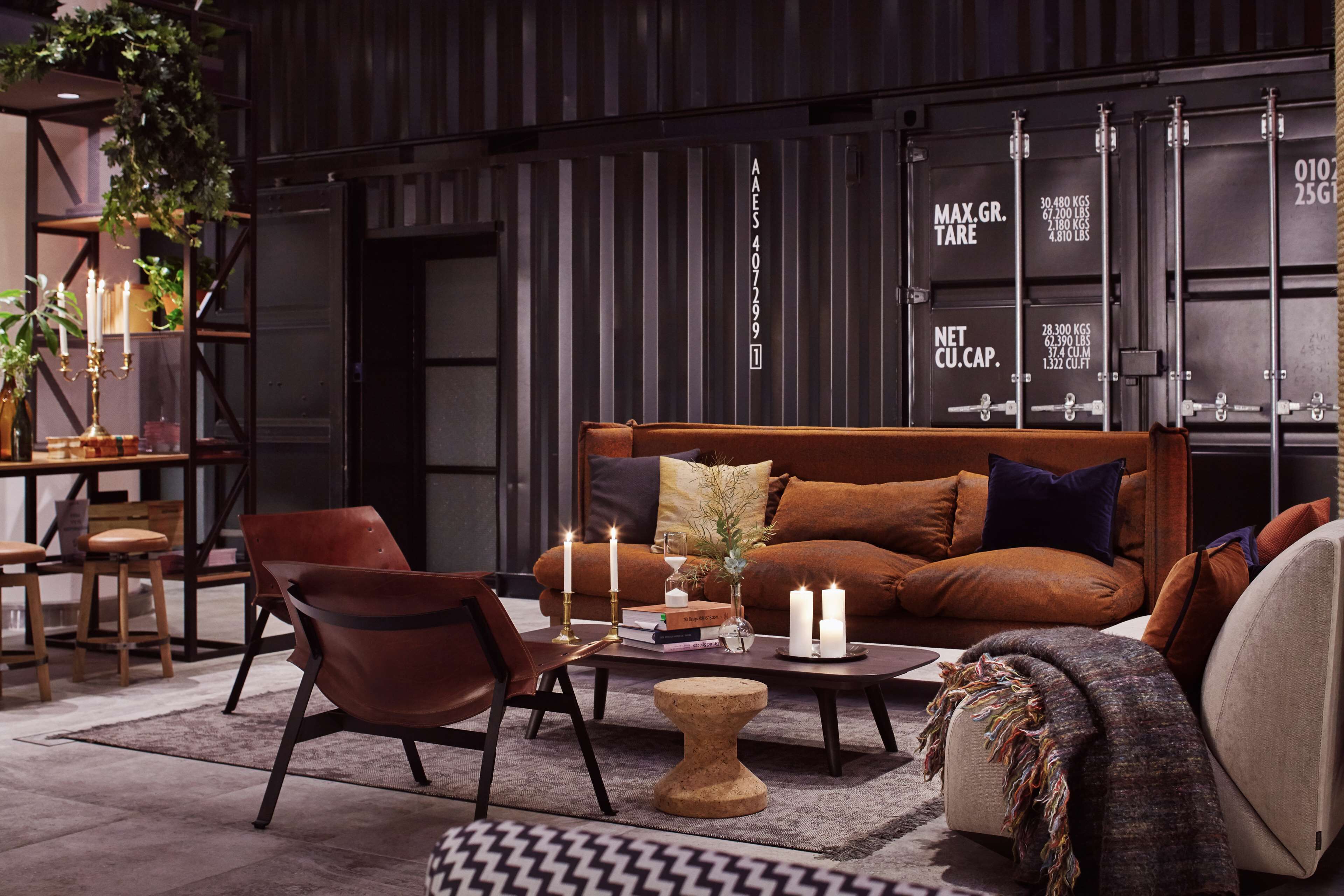 Una sala de estar moderna con un sofá marrón, sillones de cuero, una mesa de centro y una estantería.