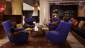 A modern lounge area with blue armchairs, a round coffee table with candles, and a fireplace. - Radisson Blu Seaside Hotel, Helsinki (Helsinki)