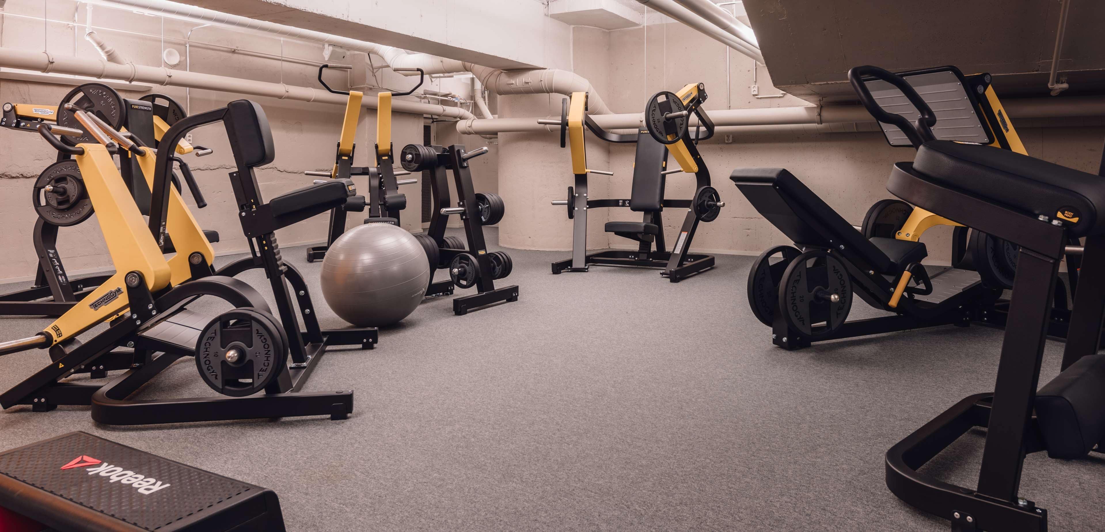 A gym with various exercise equipment, including weight machines, a rowing machine, and a stationary bike.