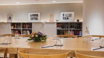 A conference room with a wooden table, chairs, a vase of flowers, and bookshelves in the background.