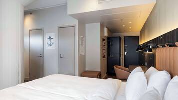 A hotel room with a large bed, a seating area, and a kitchenette.