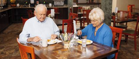 Un espace repas avec des tables et des chaises en bois, un vase rempli de fleurs et un présentoir à menus.
