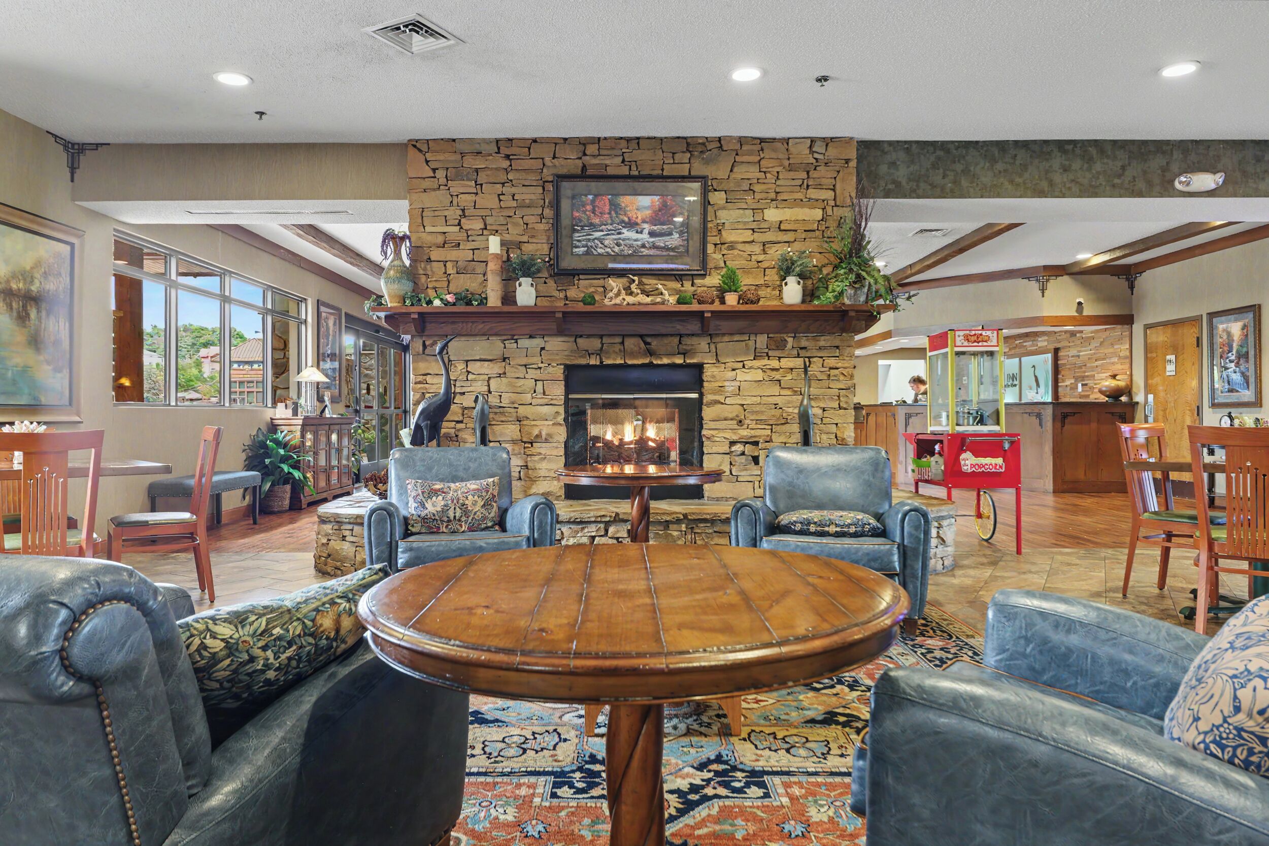 A cozy lobby with a stone fireplace, comfortable seating, and a television mounted above it.