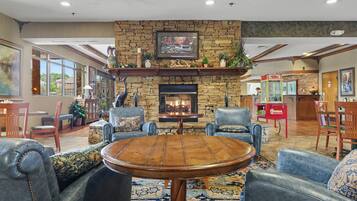 A cozy lobby with a stone fireplace, comfortable seating, and a television mounted above it.
