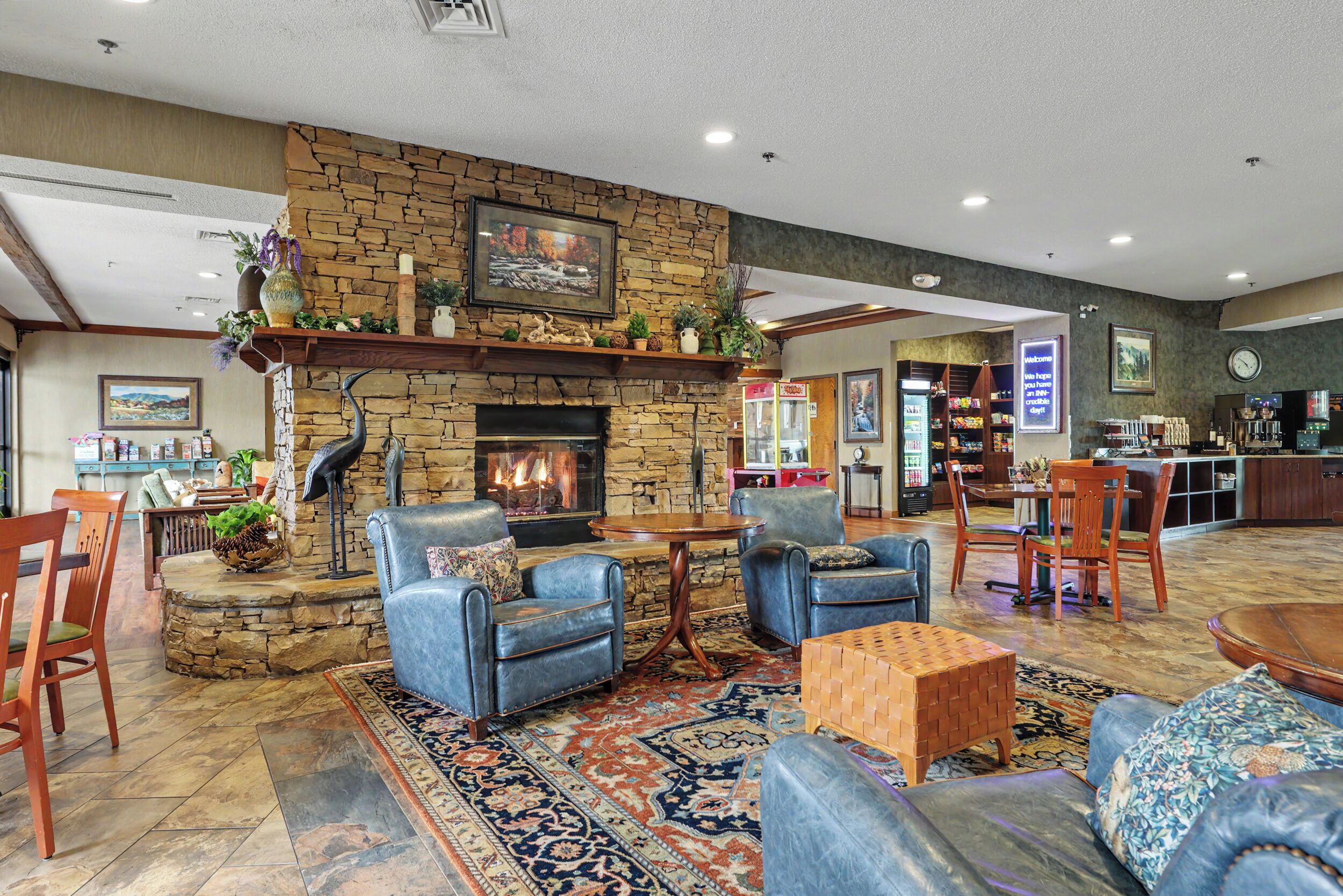 A spacious lobby with a stone fireplace, leather sofas, a wooden coffee table, and a bar area.