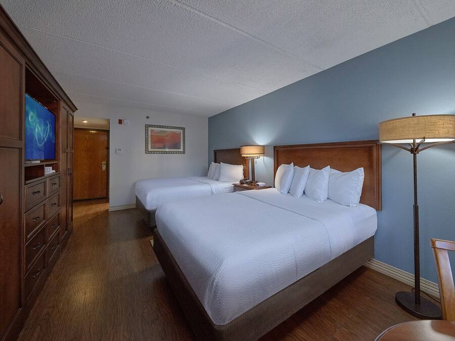 Ein Hotelzimmer mit zwei Betten, einem Fernseher, einer Lampe und einem Bild an der Wand.