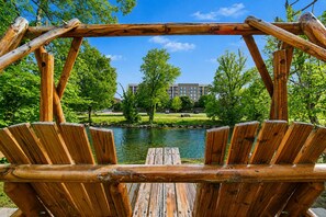 A wooden swing structure with a view of a lake and a building in the background. - The Inn On The River (Pigeon Forge)