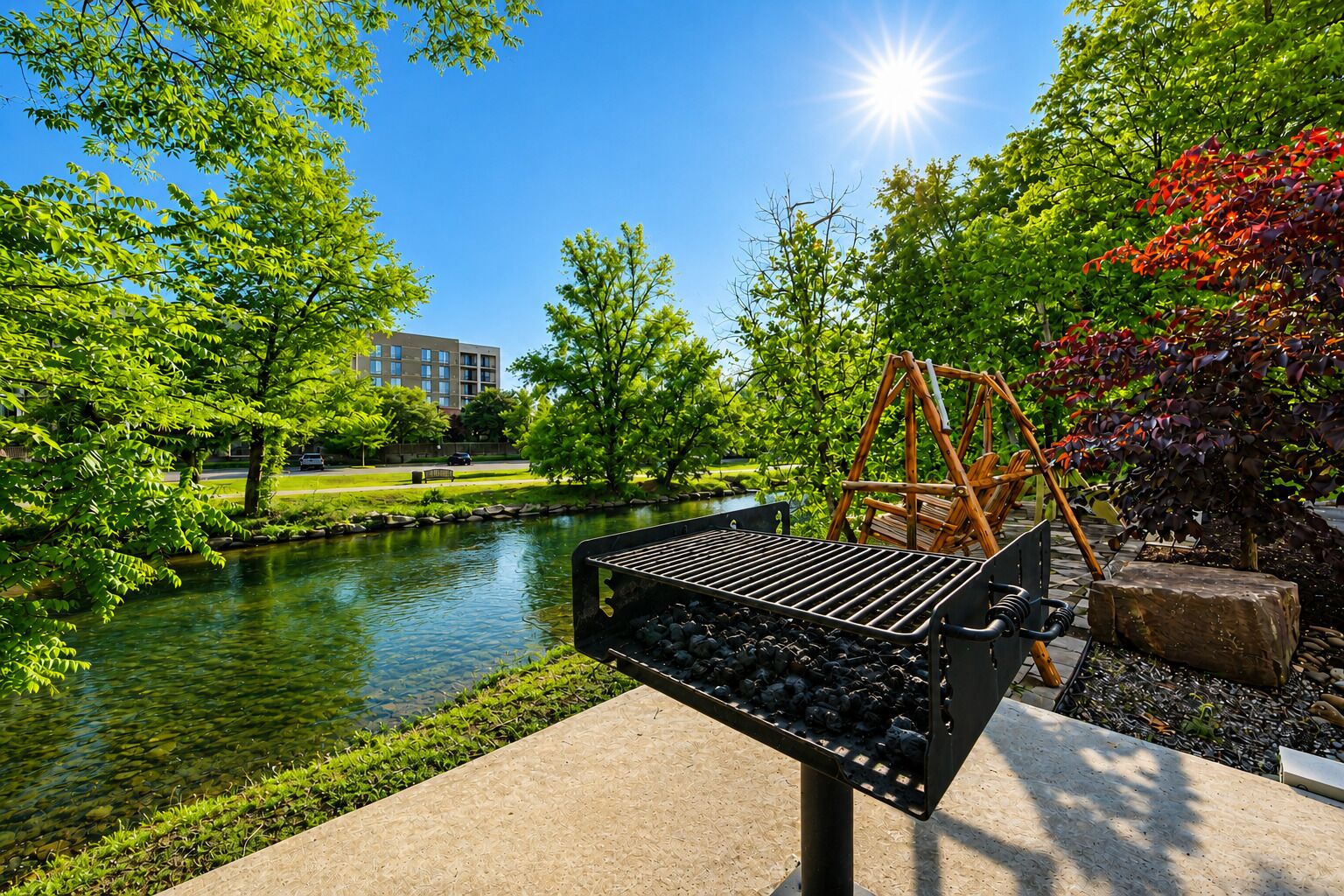 A barbecue grill outdoors with a river and trees in the background.