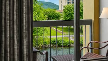 A balcony with a view of a landscaped garden, a small water feature, and a building in the background.