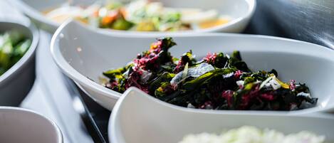 A variety of dishes in white bowls, including greens and a coleslaw.