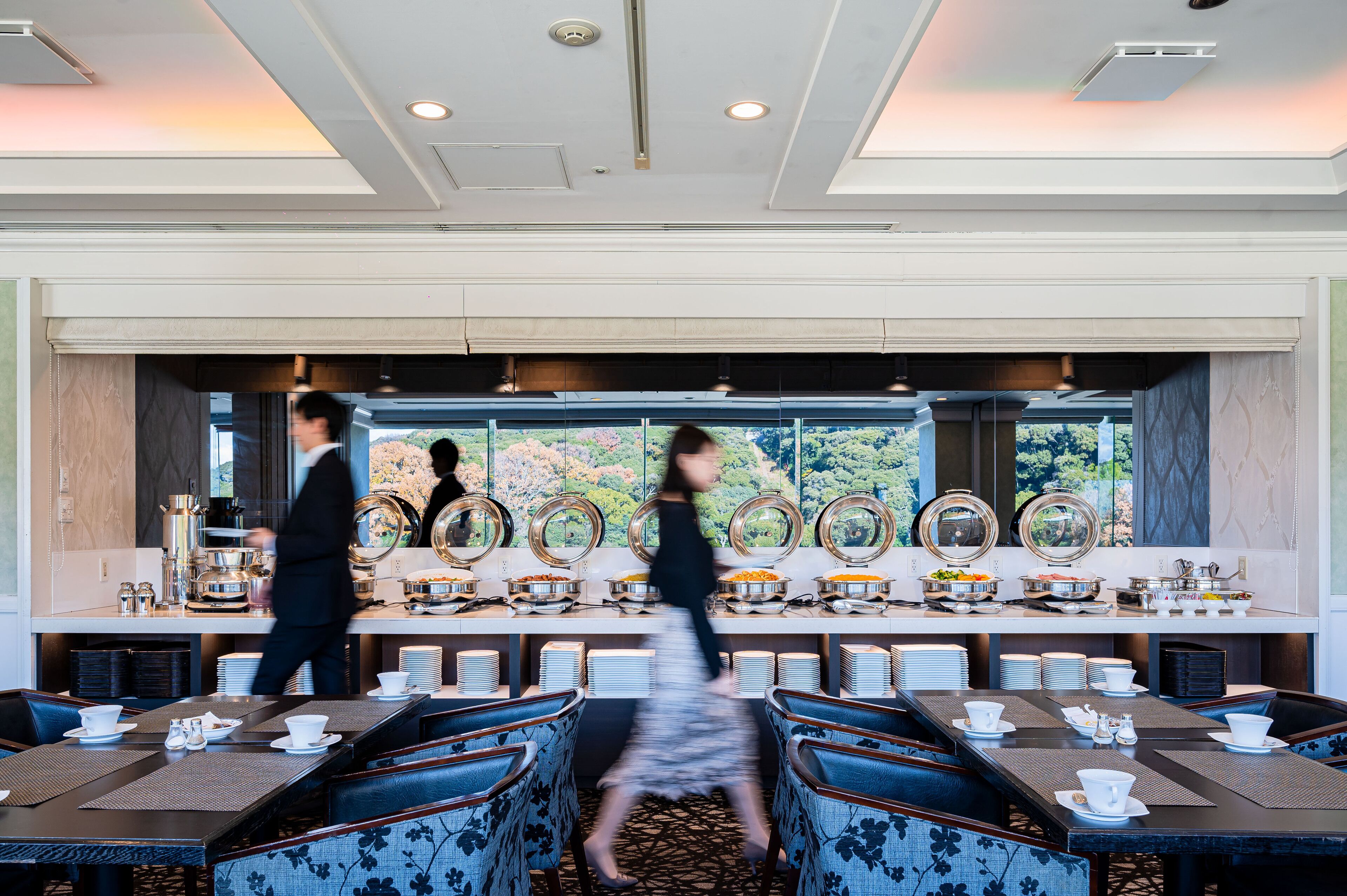 A dining area with a buffet setup, multiple dining tables, and chairs.