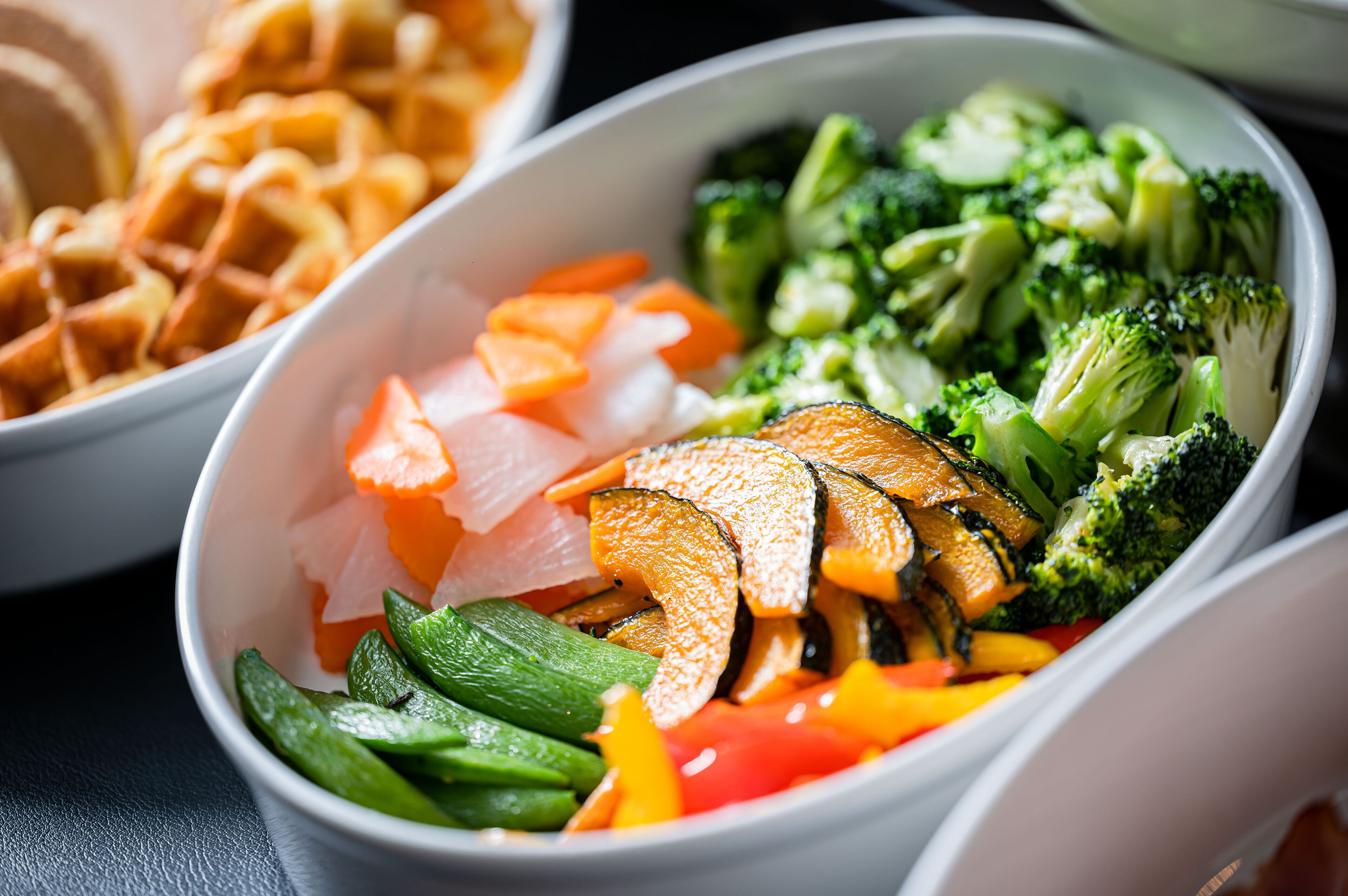 A bowl of mixed vegetables including broccoli, carrots, and zucchini.