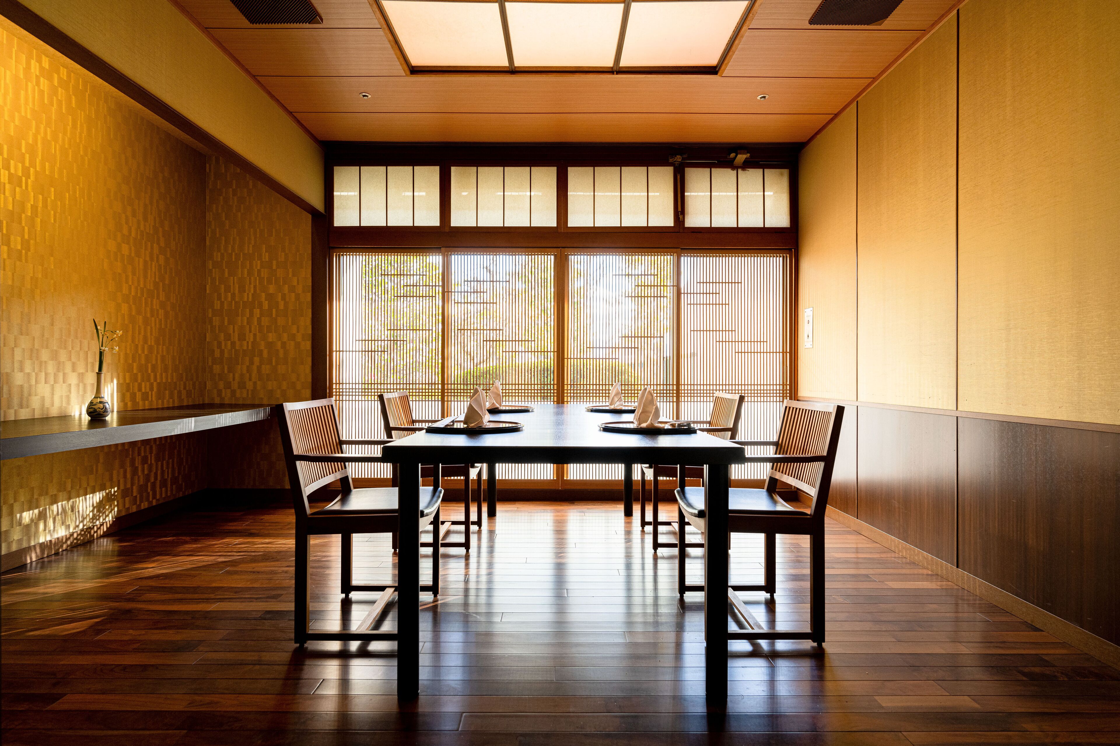 A traditional Japanese room with tatami flooring, a low table with cushions, and sliding shoji doors.