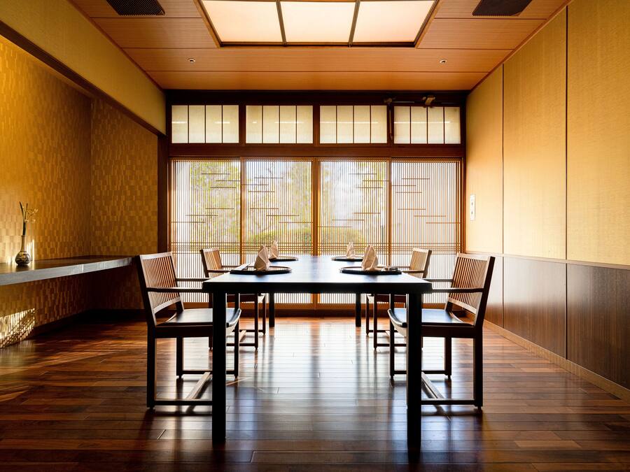 A traditional Japanese room with tatami flooring, a low table with cushions, and sliding shoji doors.