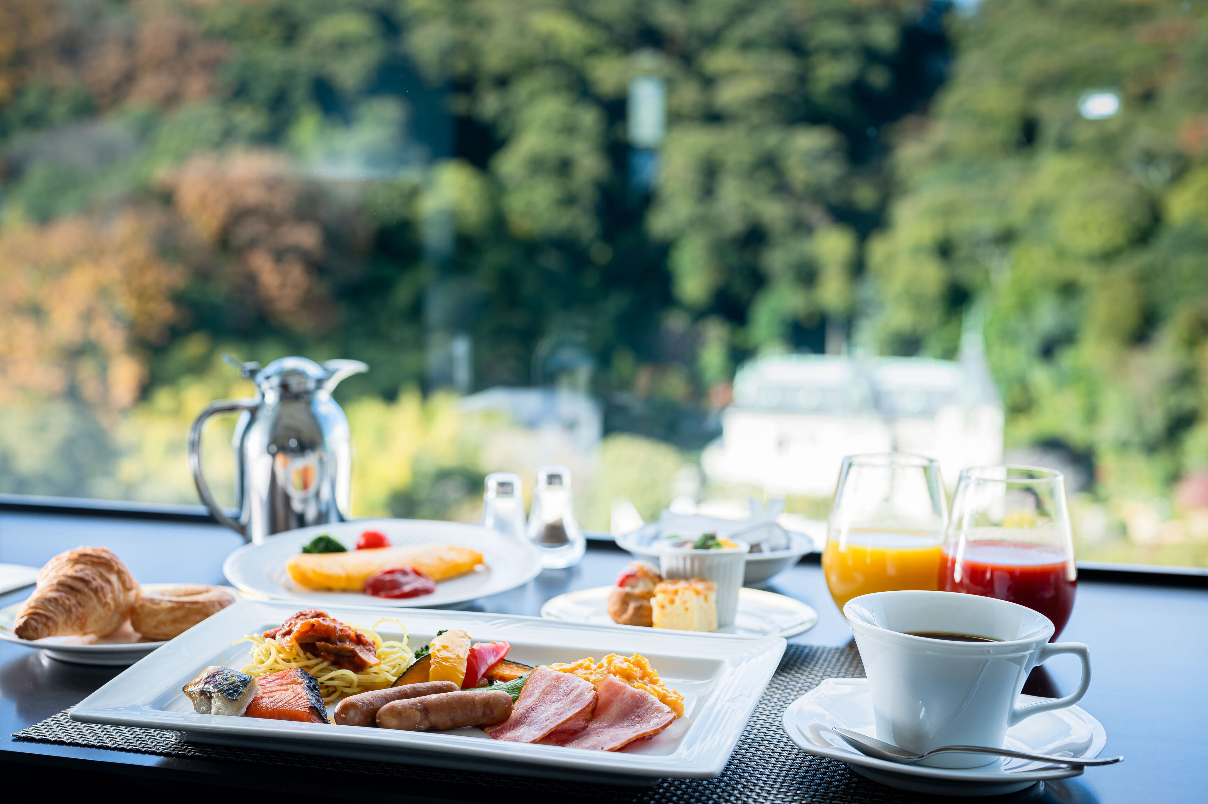 A breakfast setting with croissants, eggs, and juice, with a scenic view.