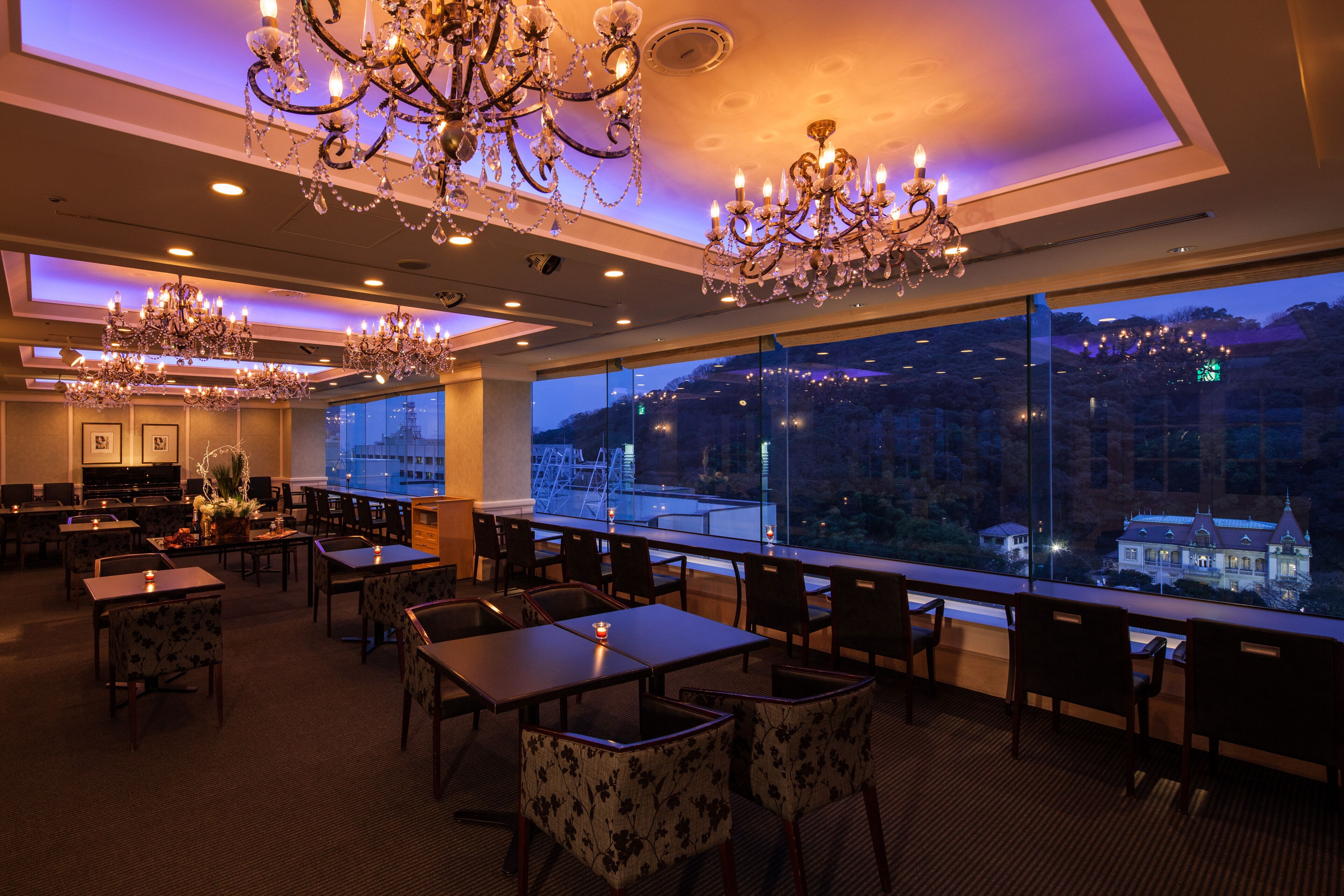 Un restaurante con varios candelabros, mesas y sillas dispuestas para comer.