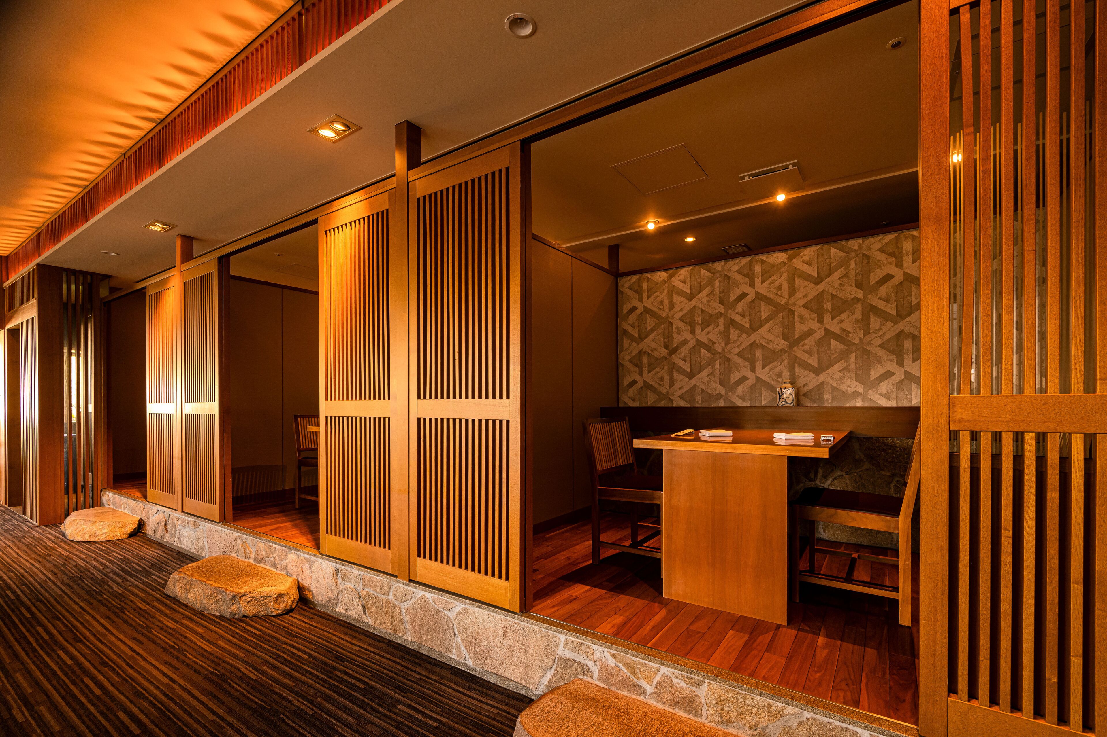 A traditional Japanese-style room with tatami flooring, sliding doors, and a low wooden table with chairs.