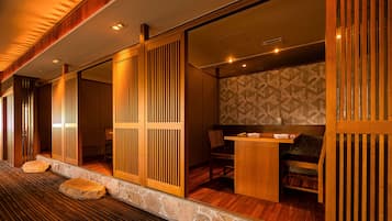A traditional Japanese-style room with tatami flooring, sliding doors, and a low wooden table with chairs.
