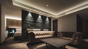 Ein modernes Wohnzimmer mit gepolstertem Sofa, Couchtisch und einer Wand als Blickfang aus Stein.