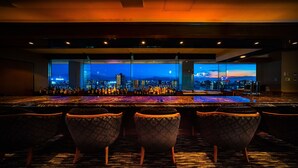 Eine Bar mit Blick auf die Stadt, verschiedenen Sitzgelegenheiten und freundlicher Beleuchtung.