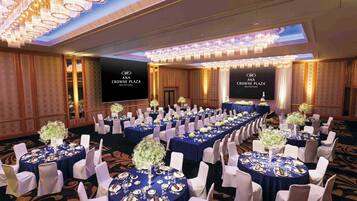 A conference room at ANA Crowne Plaza Matsuyama with round tables, white chairs, and chandeliers.